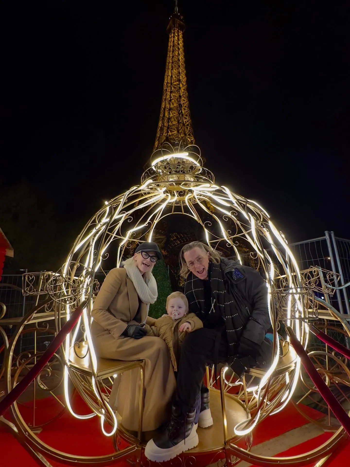 Kelly Osbourne, Sid Wilson, and their baby in a lighted carriage with the Eiffel Tower in the background.