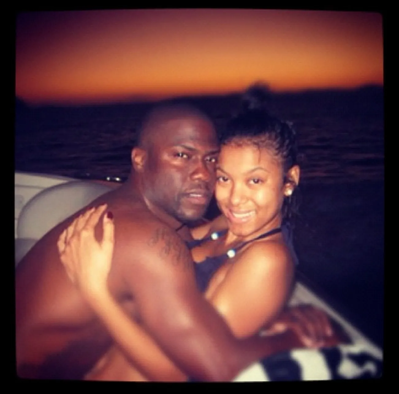 Kevin and Eniko Hart embracing each other on a boat at sunset.