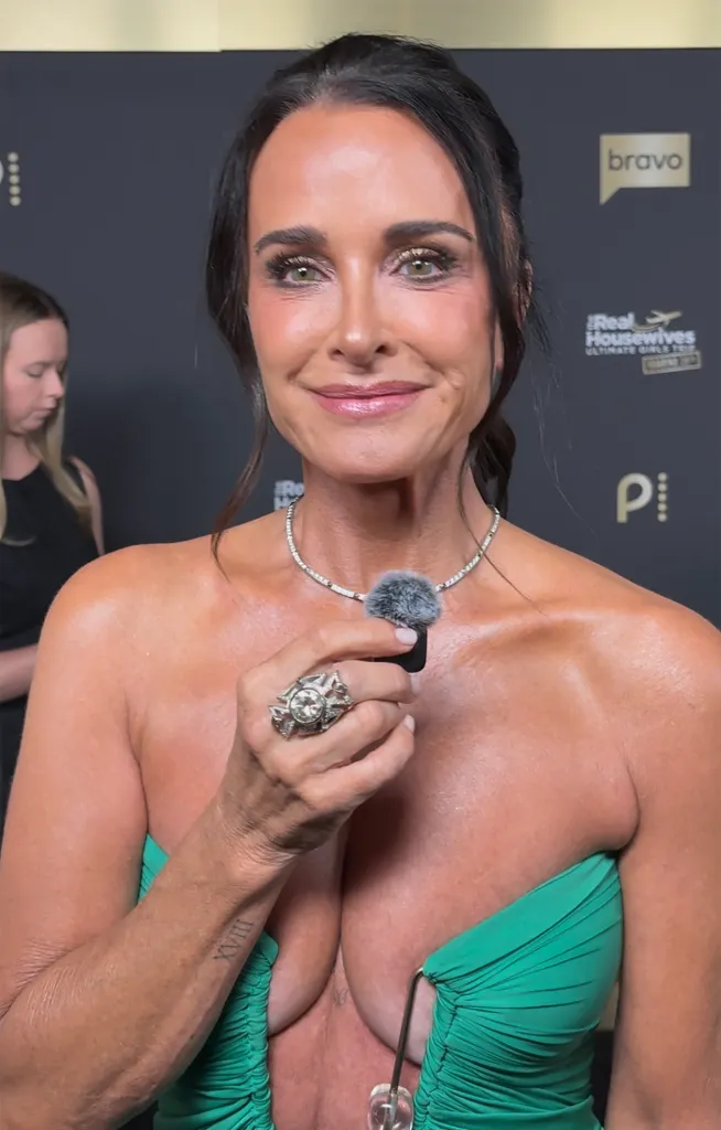 Kyle Richards smiling and holding a small microphone to her chest.