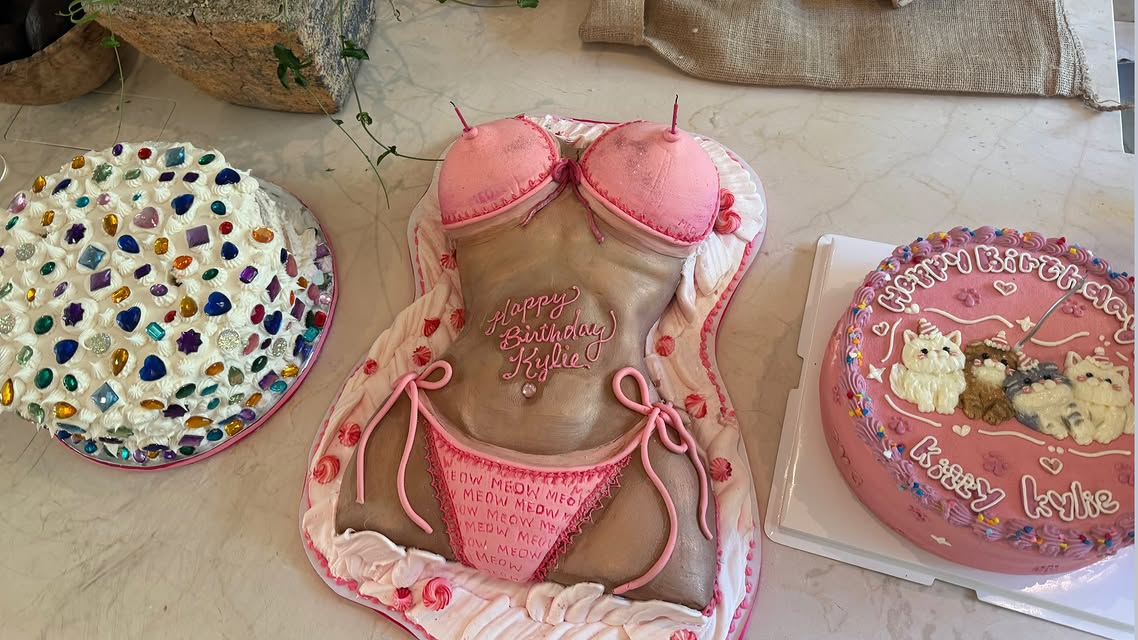 Three birthday cakes, including one shaped like a woman in a pink bikini with "Happy Birthday Kylie" written on it.