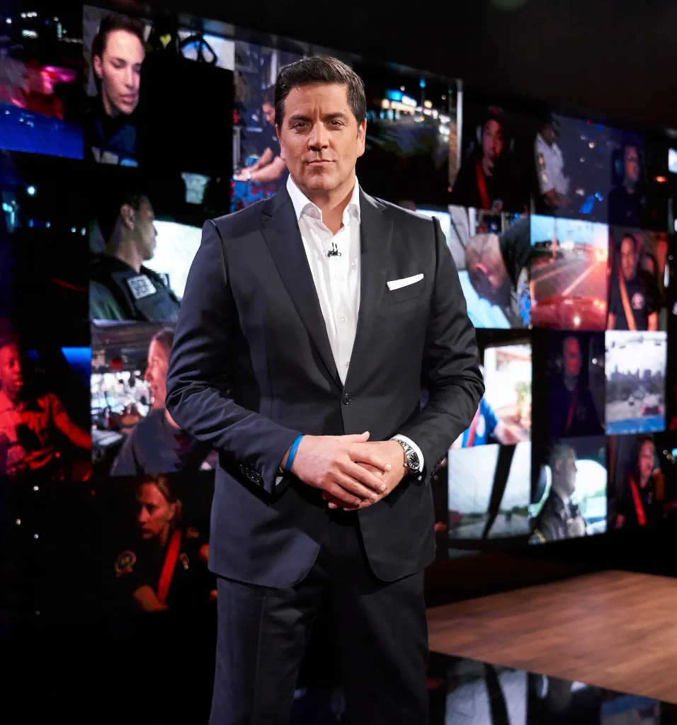 Josh Elliott, host of "First Responders Live", stands in front of a wall of screens displaying scenes of first responders.