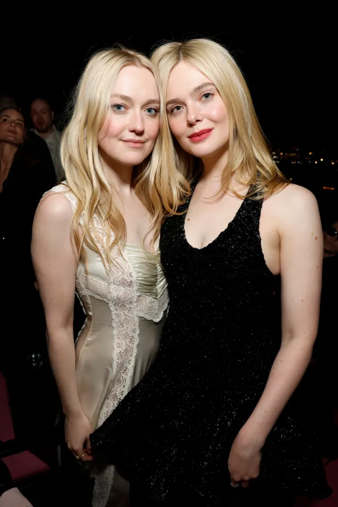 Dakota Fanning in a cream dress and Elle Fanning in a black sequined dress posing together at an event.