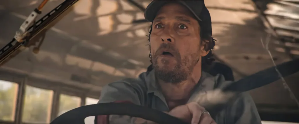 Matthew McConaughey driving a bus with a worried expression.