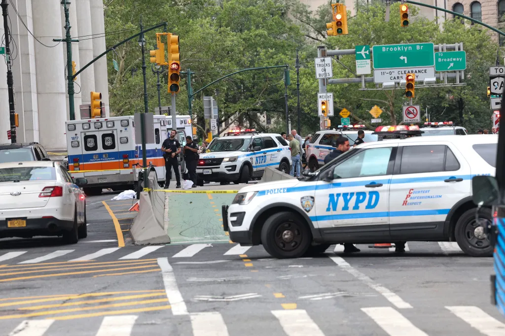 Police cars and an ambulance block off a street where a person was fatally struck while on an e-bike at the exit of the Brooklyn Bridge.