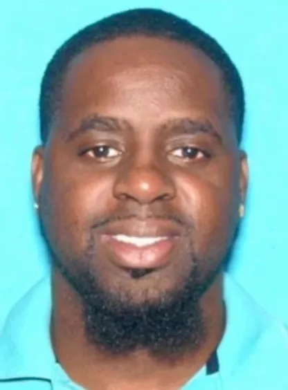 Mugshot of Troy Franklin, a 43-year-old Black man, smiling faintly against a light blue background.