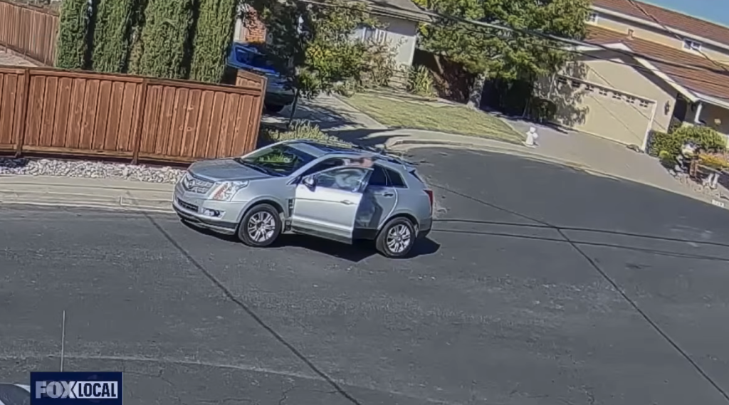 A silver SUV with its front passenger door open, stopped on a residential street.
