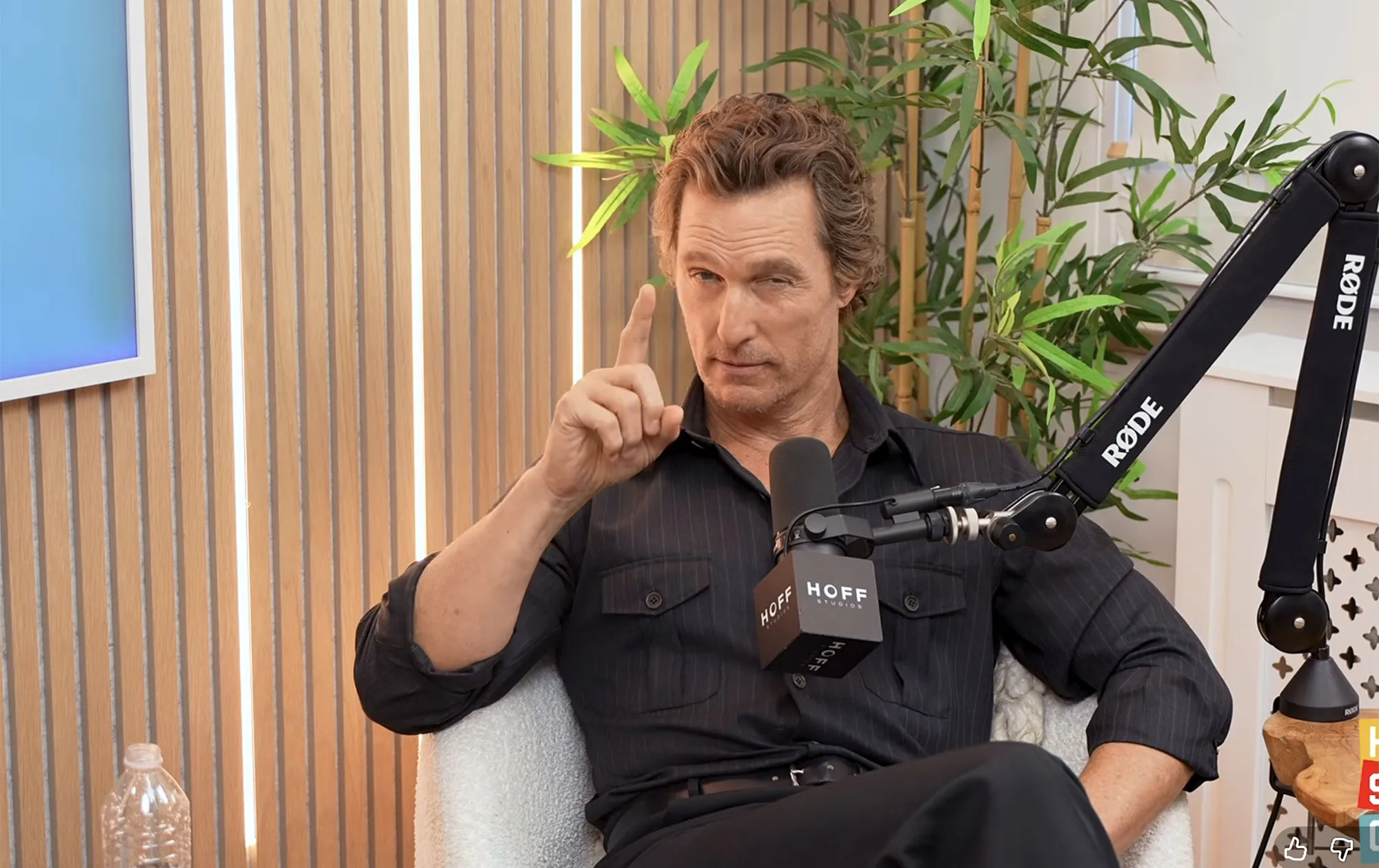 Matthew McConaughey winks while pointing his finger up during a podcast interview.