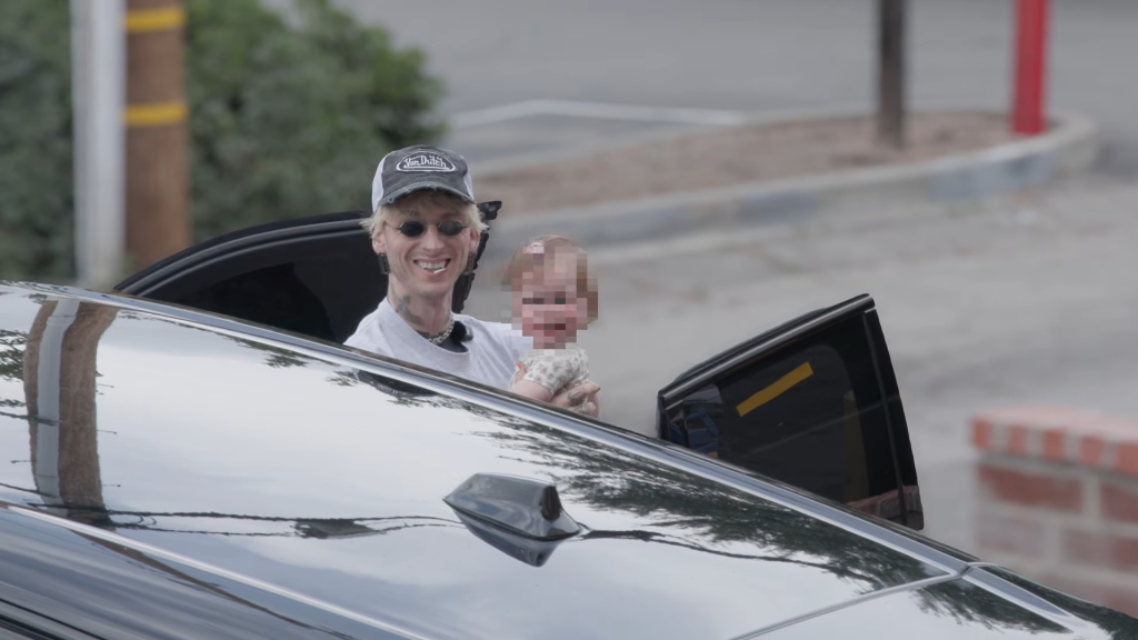 Machine Gun Kelly holding Meghan Fox's daughter, Saga, in a car.