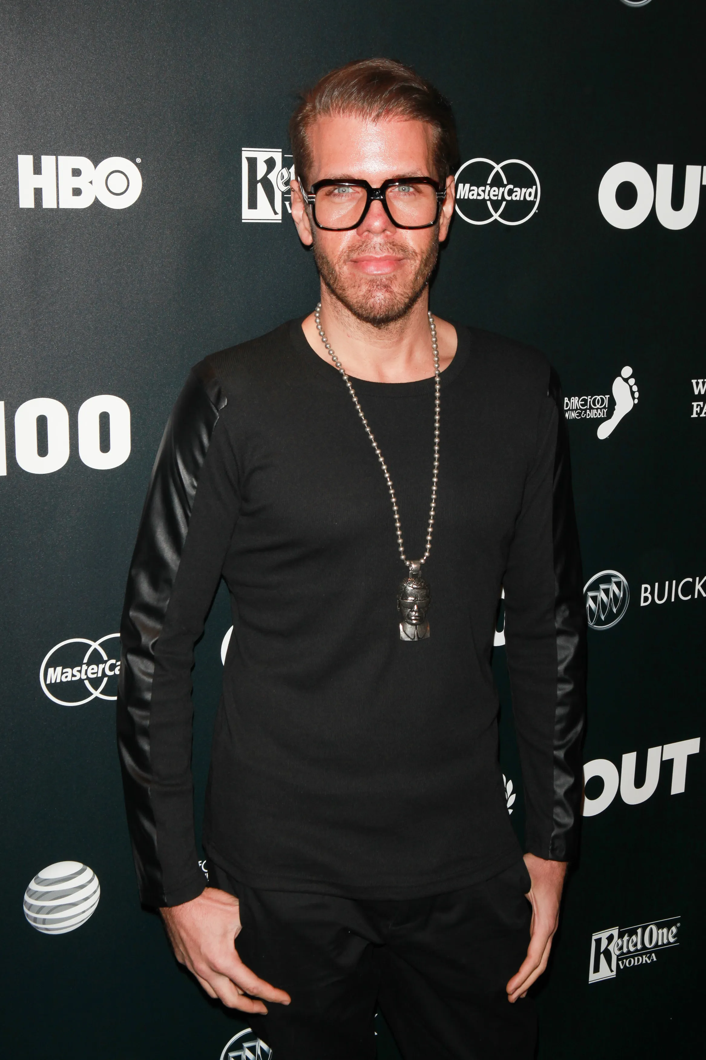 Perez Hilton poses in a black shirt and black framed glasses against a dark background with various company logos.