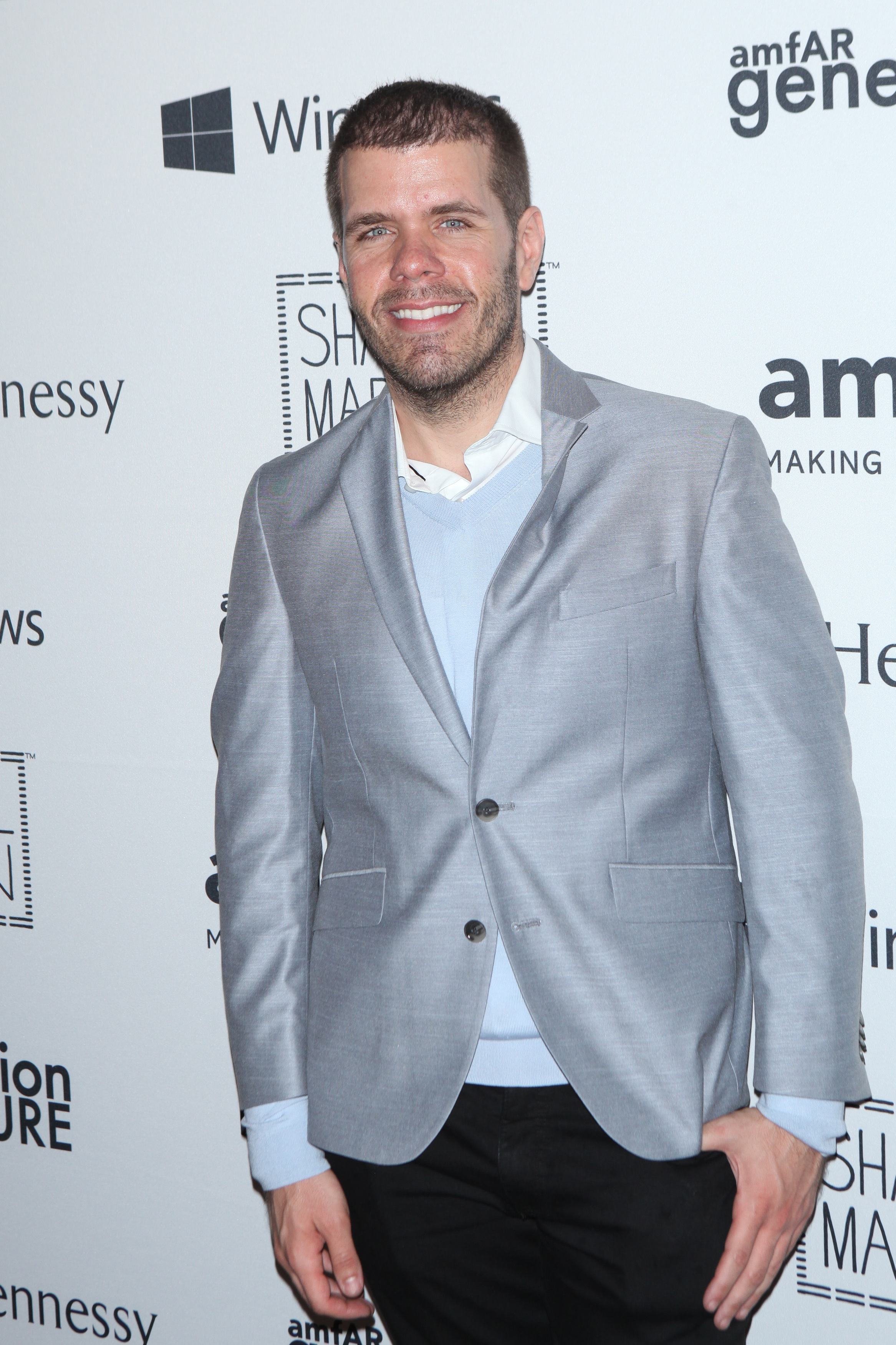 Perez Hilton wearing a light blue sweater and a light gray blazer at an event.
