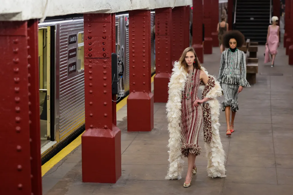 Models presenting creations during the Chanel Metiers d'art 2026 Show on a subway platform.