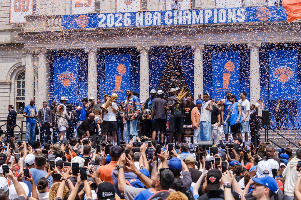 The New York Knicks basketball team is honored at City Hall during a ceremony, with players holding up the championship trophy.