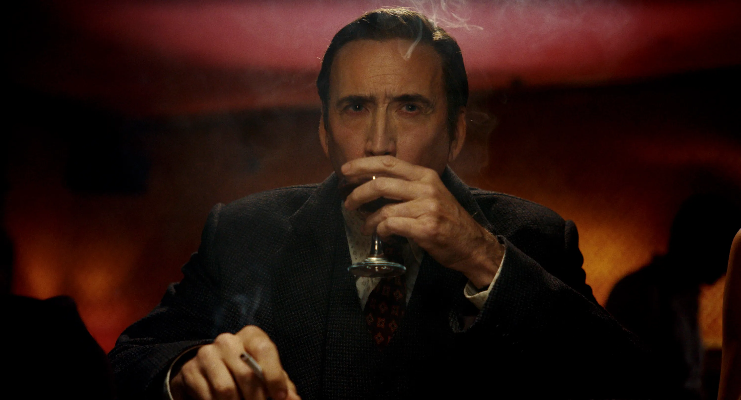 Nicolas Cage as Ben Reilly / The Spider, drinking and smoking in a closeup shot.