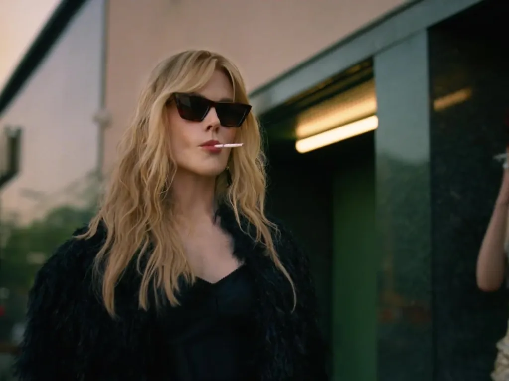 Nicole Kidman in black sunglasses with a cigarette in her mouth.