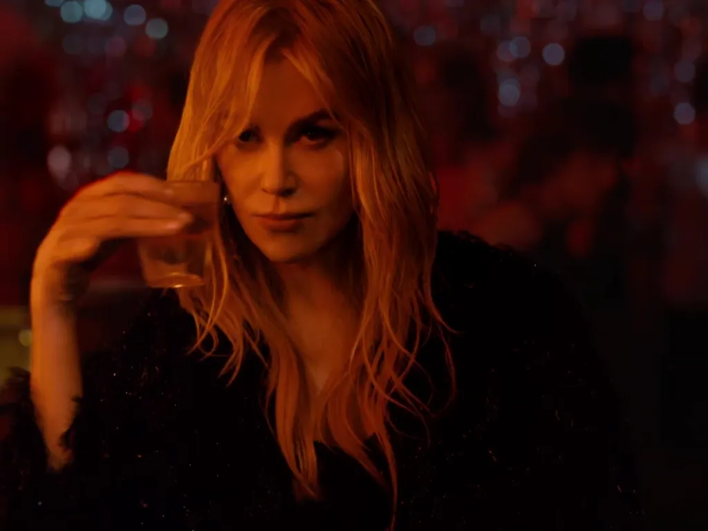 Nicole Kidman holding a drink in a dimly lit setting.