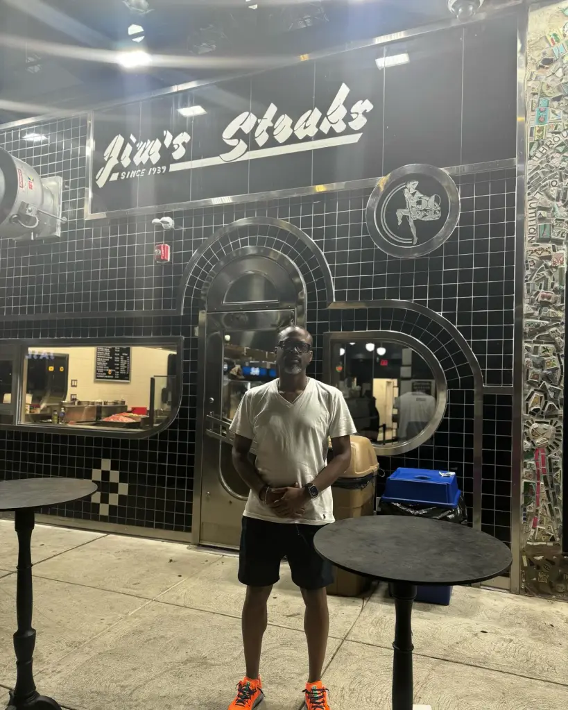 A man stands in front of Jim's Steaks.