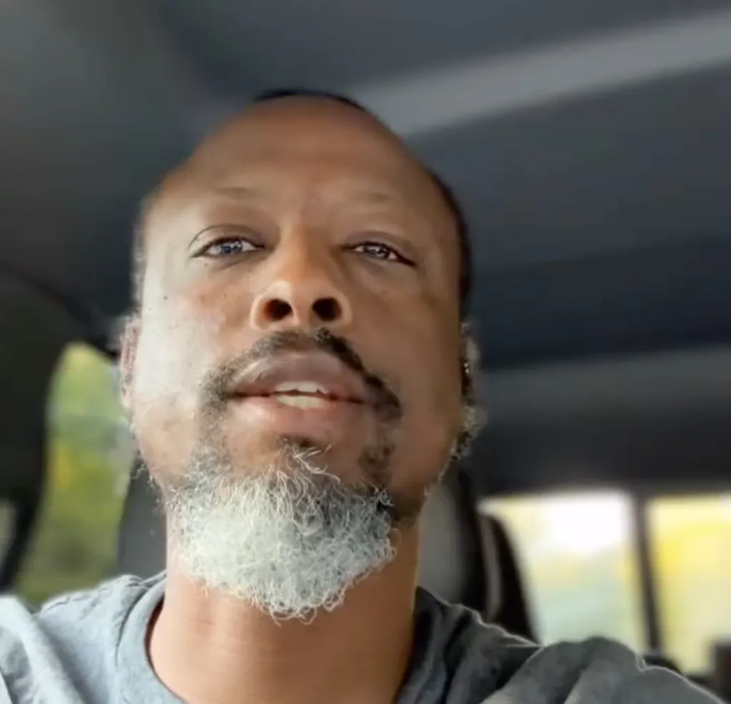 Man with a gray beard and mustache, looking into the camera.