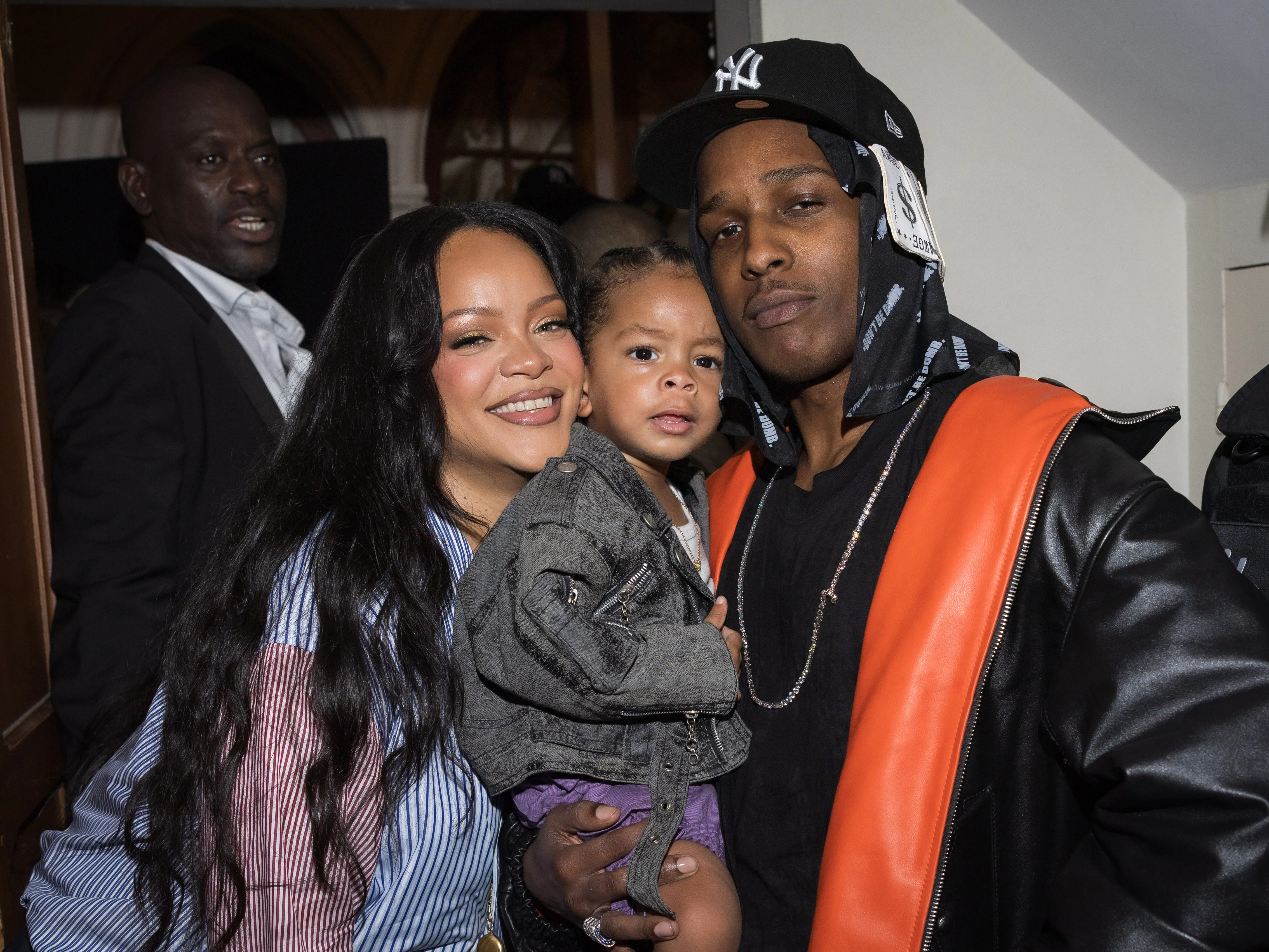 Rihanna smiles, while A$AP Rocky holds their son Riot at Paris Fashion Week.