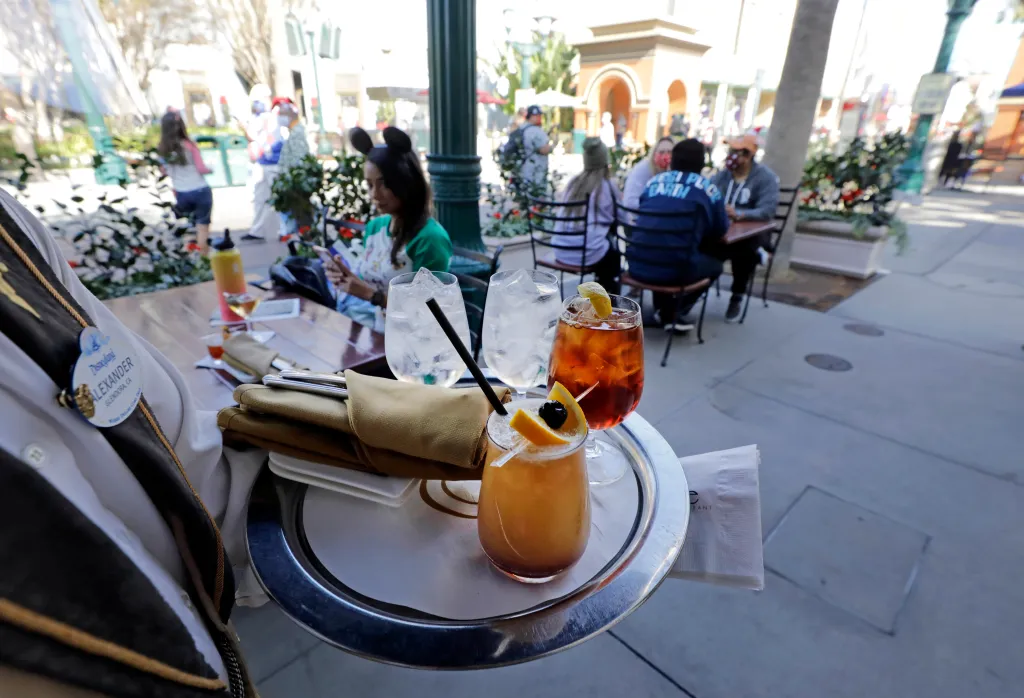 A server carrying a tray of three drinks, two with ice and one with a black olive and orange slice, at Carthay Circle Restaurant in Anaheim, California.