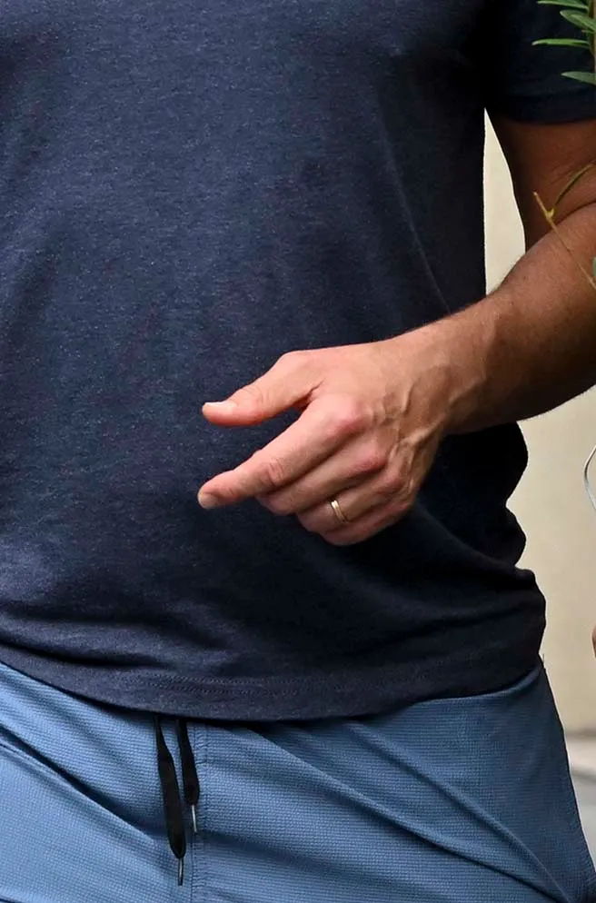 Bradley Cooper's hand with a subtle wedding band on his left ring finger.