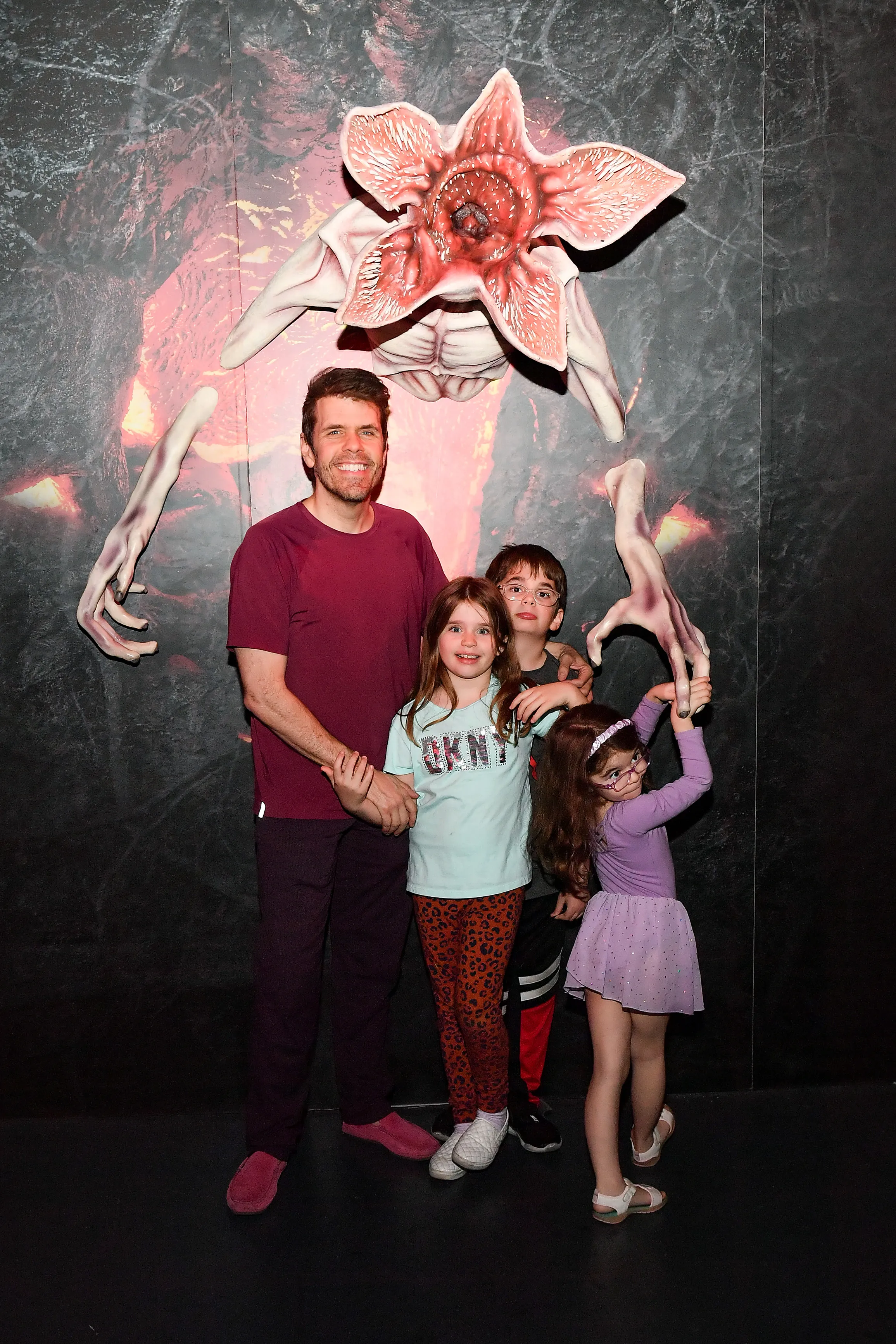 Perez Hilton with his three children in front of a Demogorgon display.