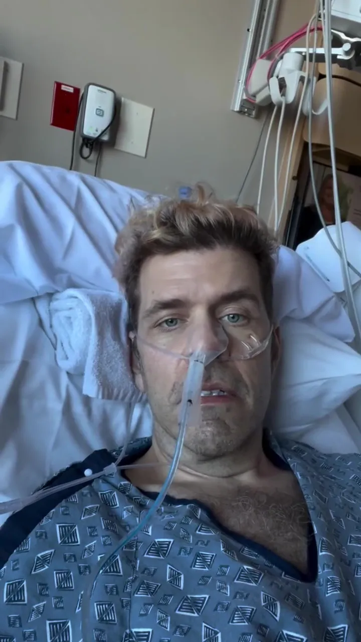 Perez Hilton in a hospital gown and oxygen cannula.