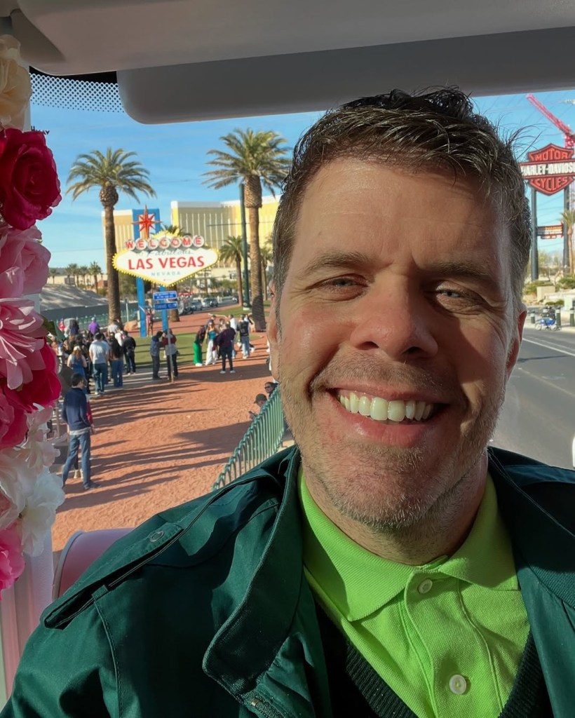 Perez Hilton smiling in a selfie with the "Welcome to Fabulous Las Vegas" sign in the background.