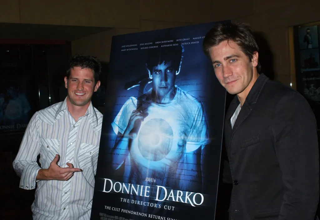 Richard Kelly and Jake Gyllenhaal next to a poster for 