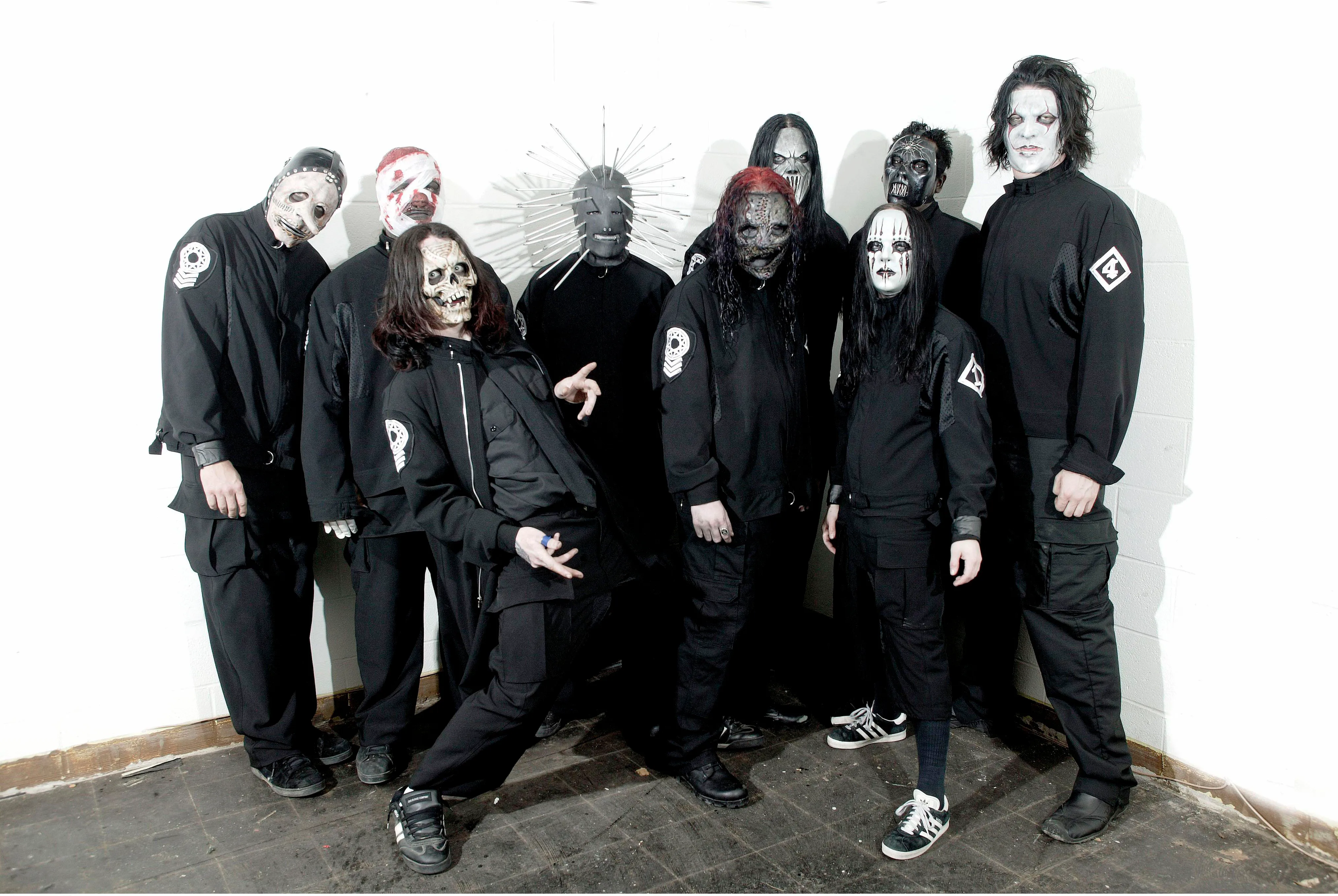 Nine members of Slipknot posing for a group photo in their stage costumes.