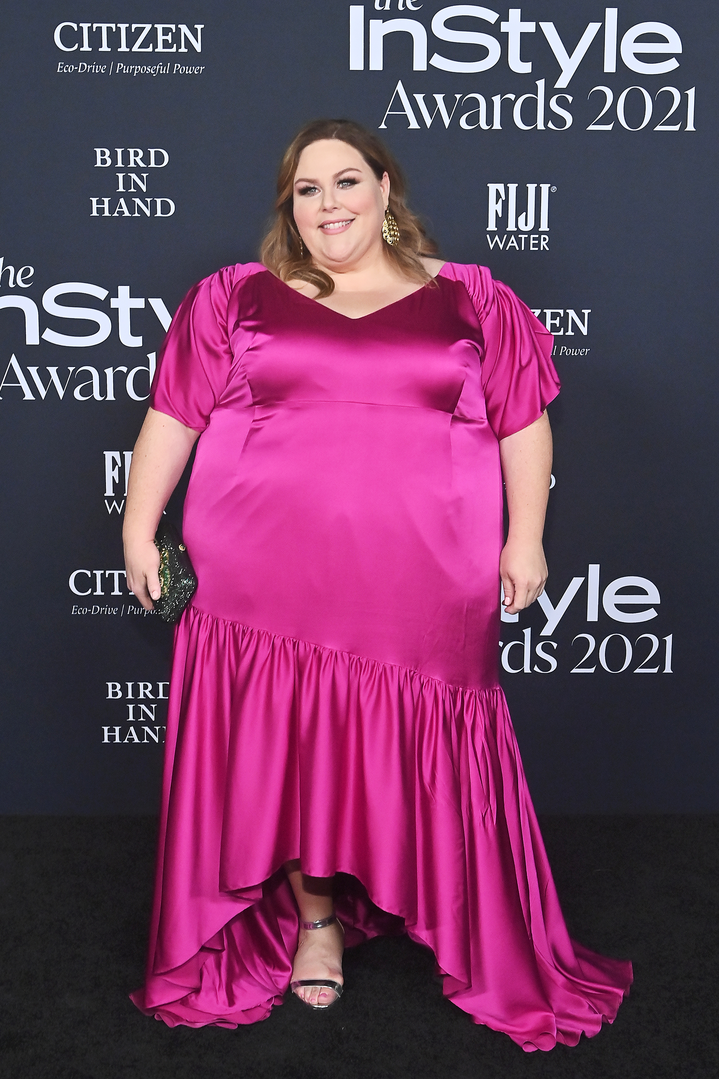 Chrissy Metz smiling on the red carpet in a magenta satin dress.