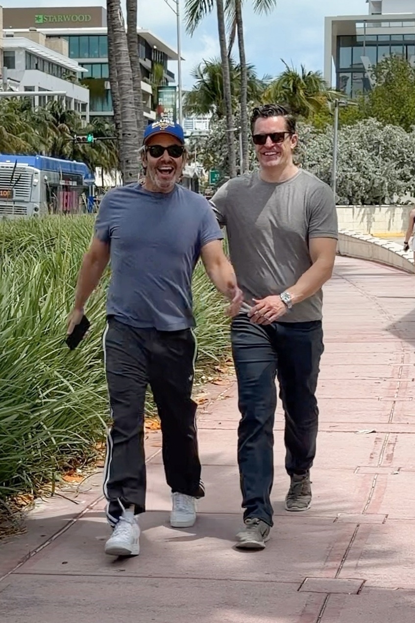 Andy Cohen and Kevin Sobieski walking and smiling during a Miami vacation.