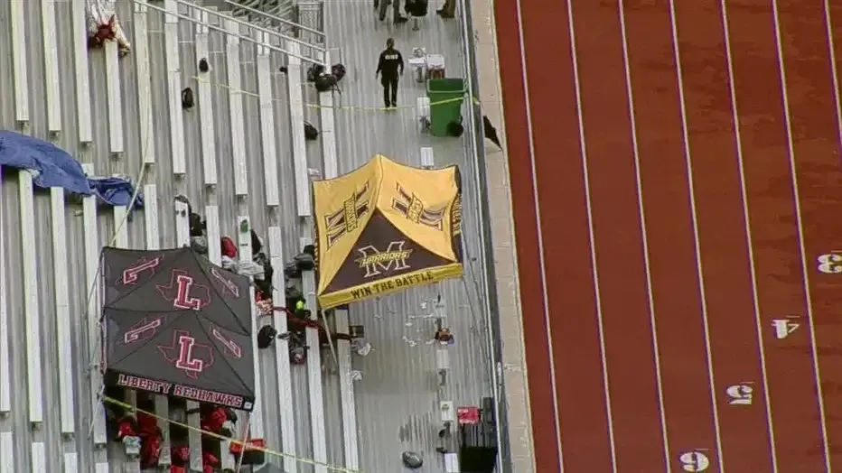 Aerial view of a stadium with two tents on bleachers next to a running track, with "LIBERTY REDHAWKS" on one and "WARRIORS WIN THE BATTLE" on the other.