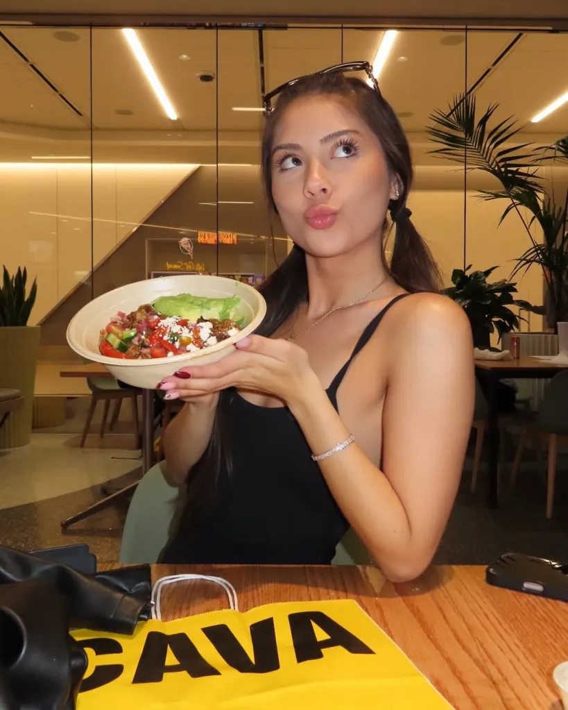 A woman holding a bowl of food from Cava.
