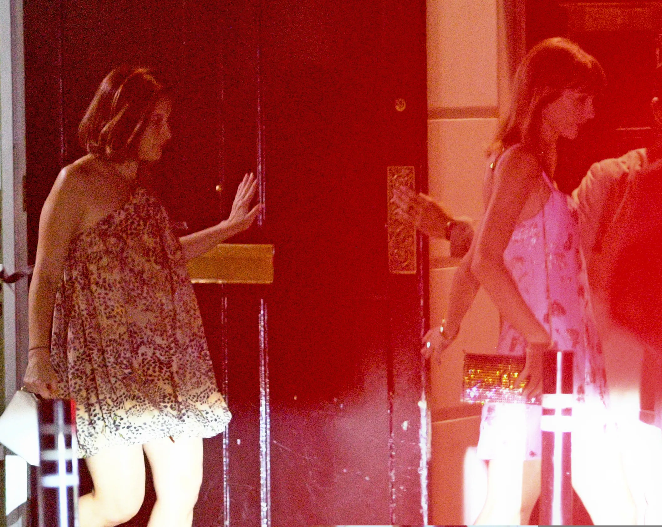 Taylor Swift in a pink and purple floral mini dress with spaghetti straps and a gold shoulder bag.