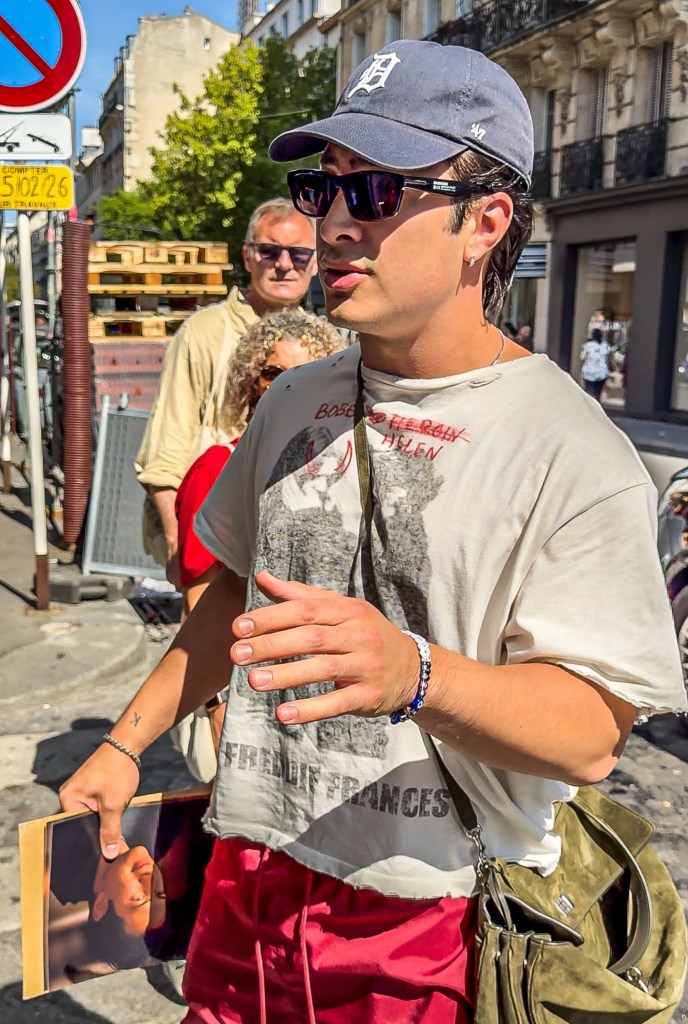 Hudson Williams holding a headshot and confronting an autograph dealer in Paris.