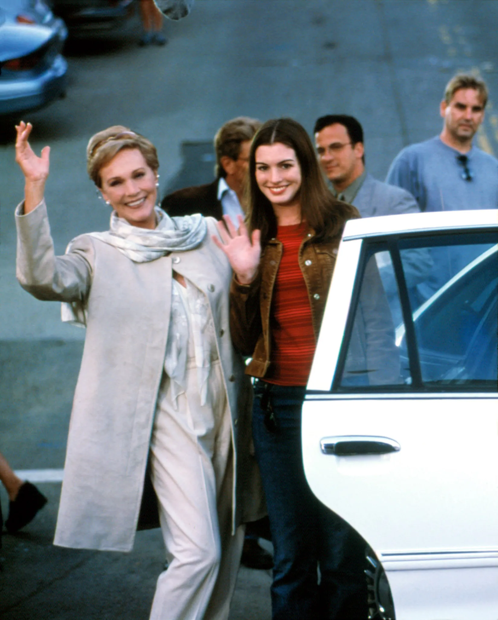 Julie Andrews and Anne Hathaway waving from a car in a scene from "The Princess Diaries".