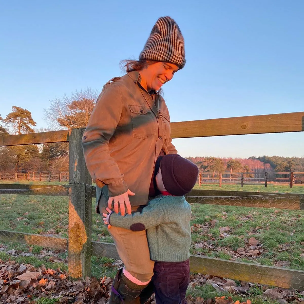 Princess Eugenie smiling at her son August who is hugging her leg.