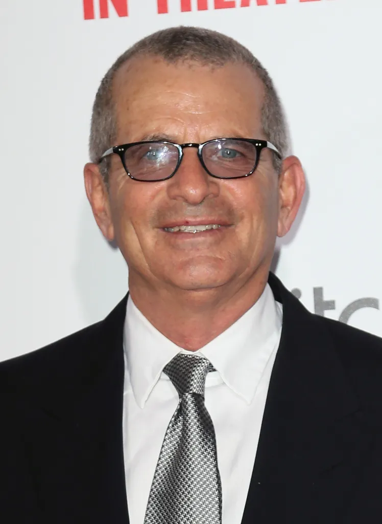 Producer Adam Fields, wearing glasses, a suit, and a patterned tie.