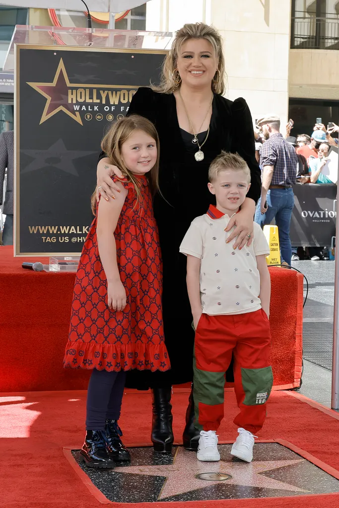 Kelly Clarkson smiles with her two children, River Rose and Remington Alexander Blackstock, standing next to her new Hollywood Walk of Fame star.
