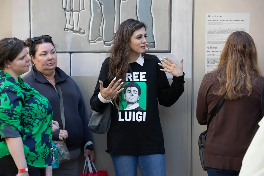 People outside 100 Centre St. for the Luigi Mangione trial, one wearing a "Free Luigi" shirt.