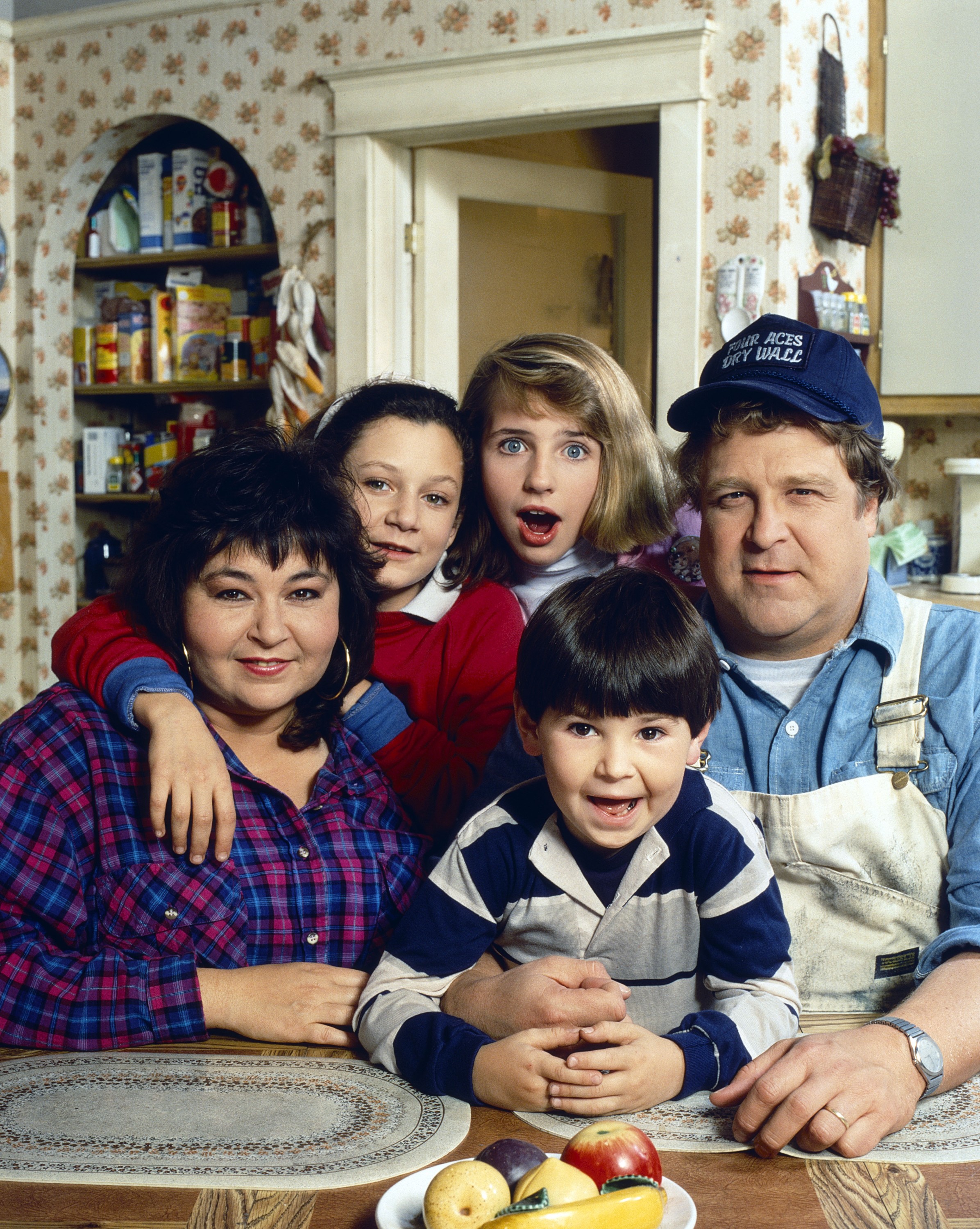 Cast photo of Roseanne Barr, Sara Gilbert, Alicia Goranson, Michael Fishman, and John Goodman from "Roseanne".
