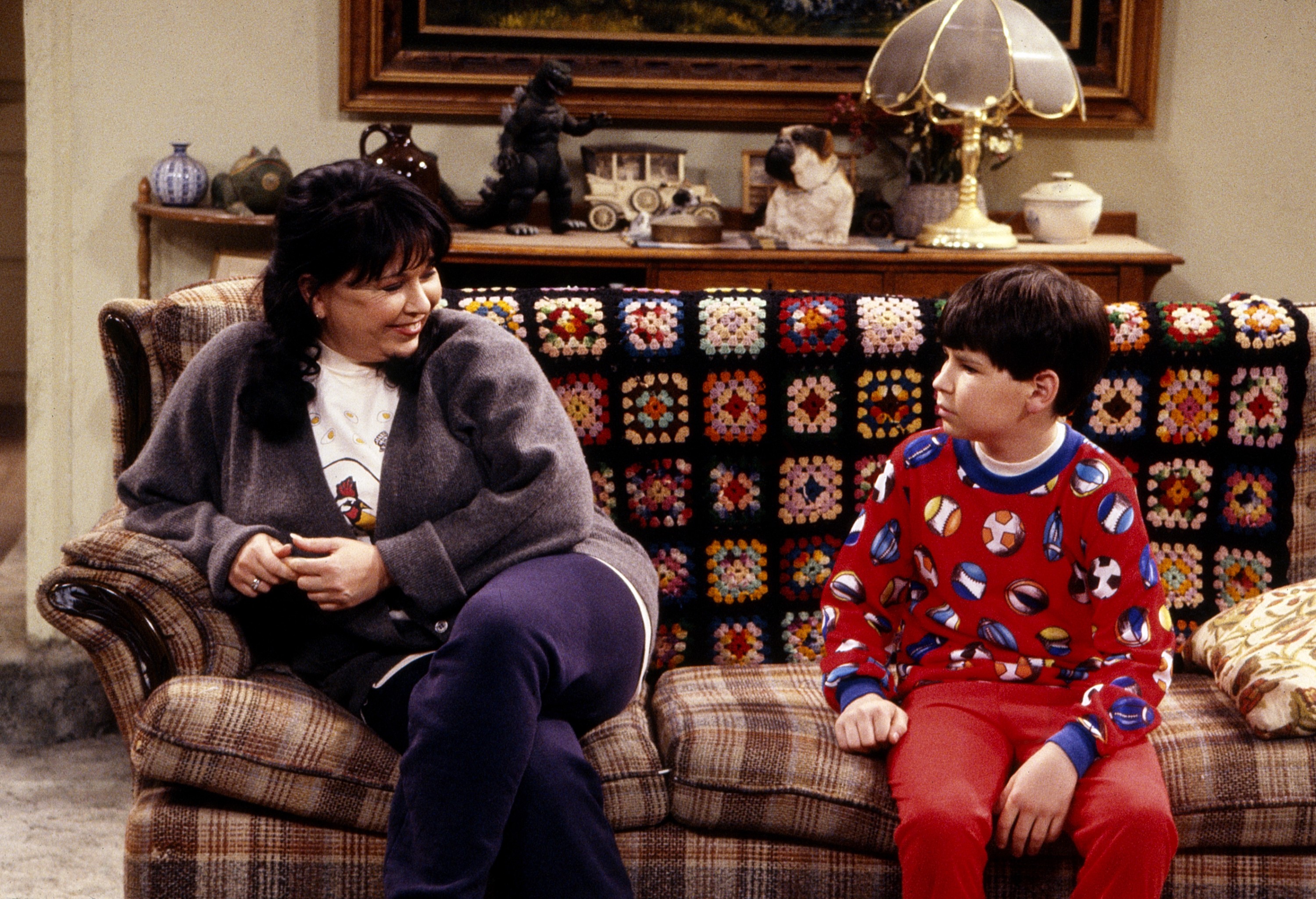 Roseanne and Michael Fishman from "Roseanne" sit on a sofa.