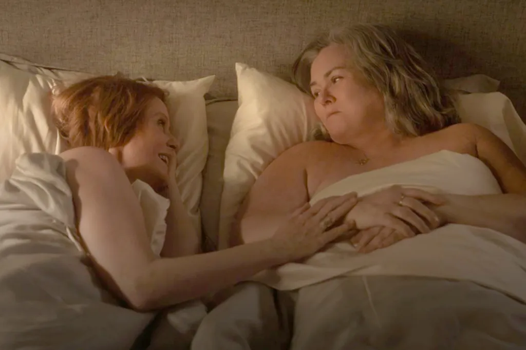 Cynthia Nixon and Rosie O'Donnell lying in bed, looking at each other, in a scene from