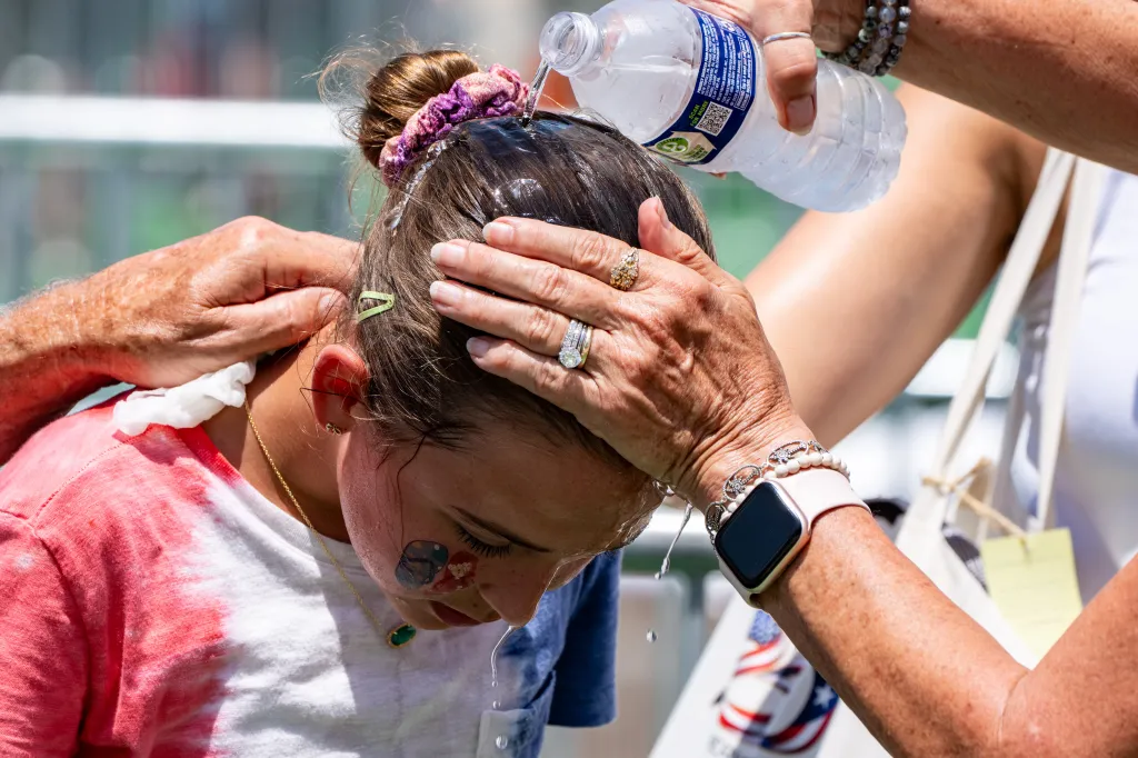 Ruth, 11, gets cold water poured on her head to cool off at the Great American State Fair.