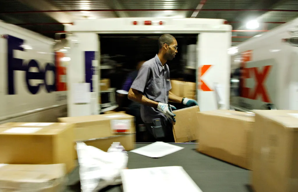 A FedEx employee holds a package in a FedEx facility.