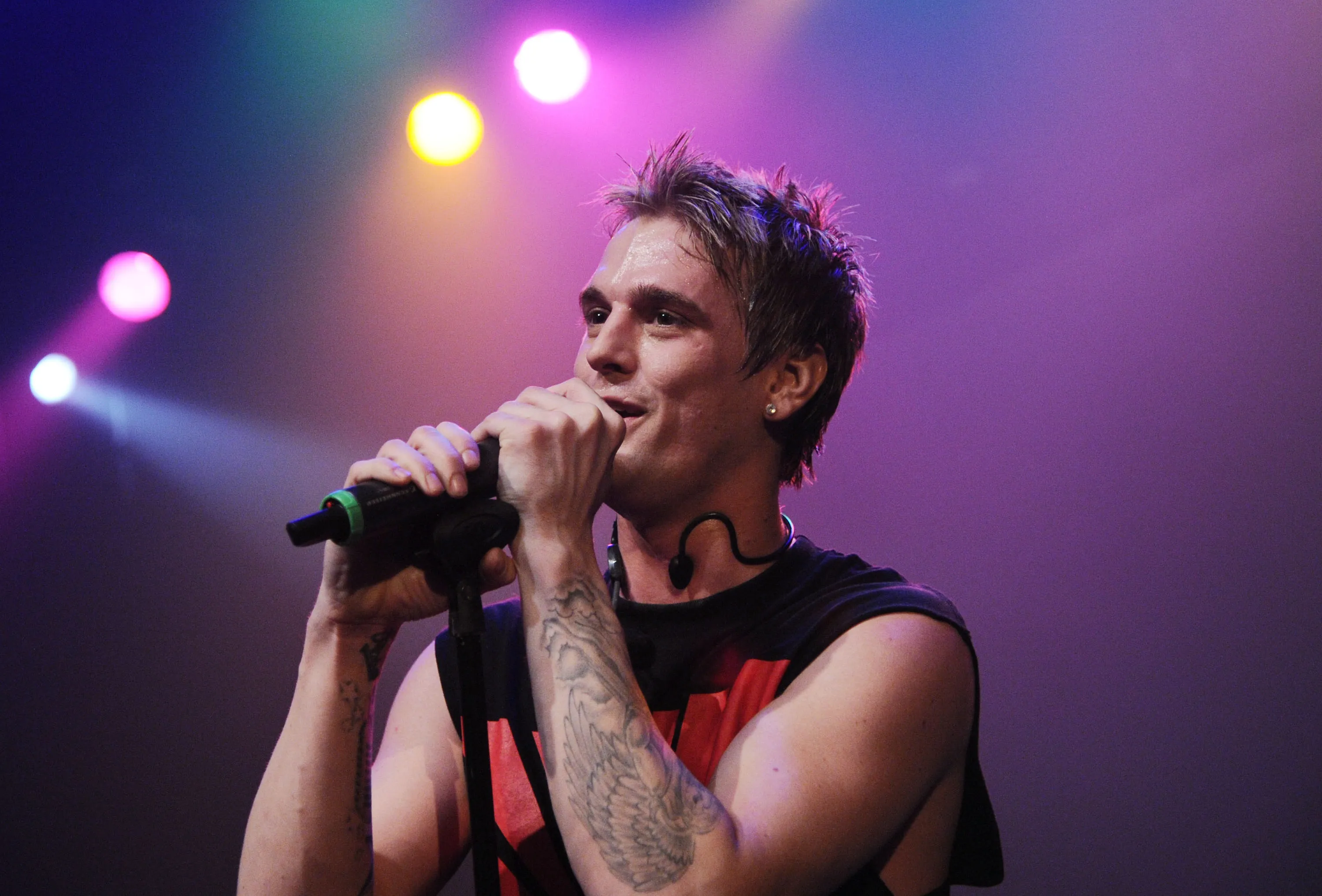 Aaron Carter singing into a microphone on stage.