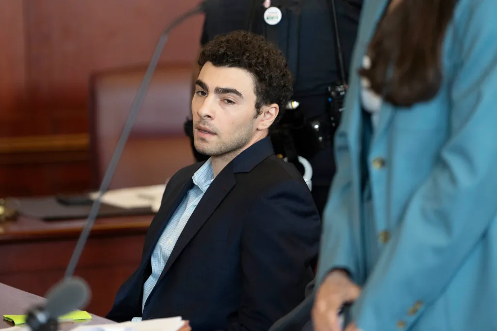 Luigi Mangione, accused of killing UnitedHealthcare CEO Brian Thompson, looks up while sitting in a courtroom.