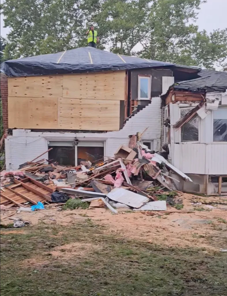 A large tree brought down by storms rests on a home, trapping dozens of cats inside, on Monday in Westbury.