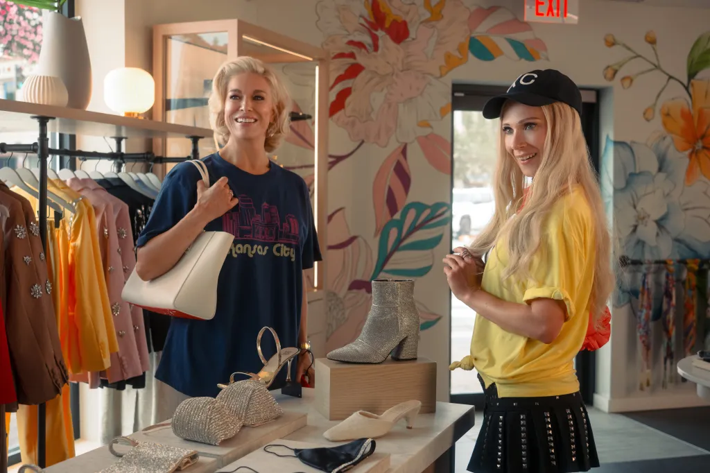 Two women standing in a boutique, one wearing a Kansas City t-shirt, the other a black baseball cap.