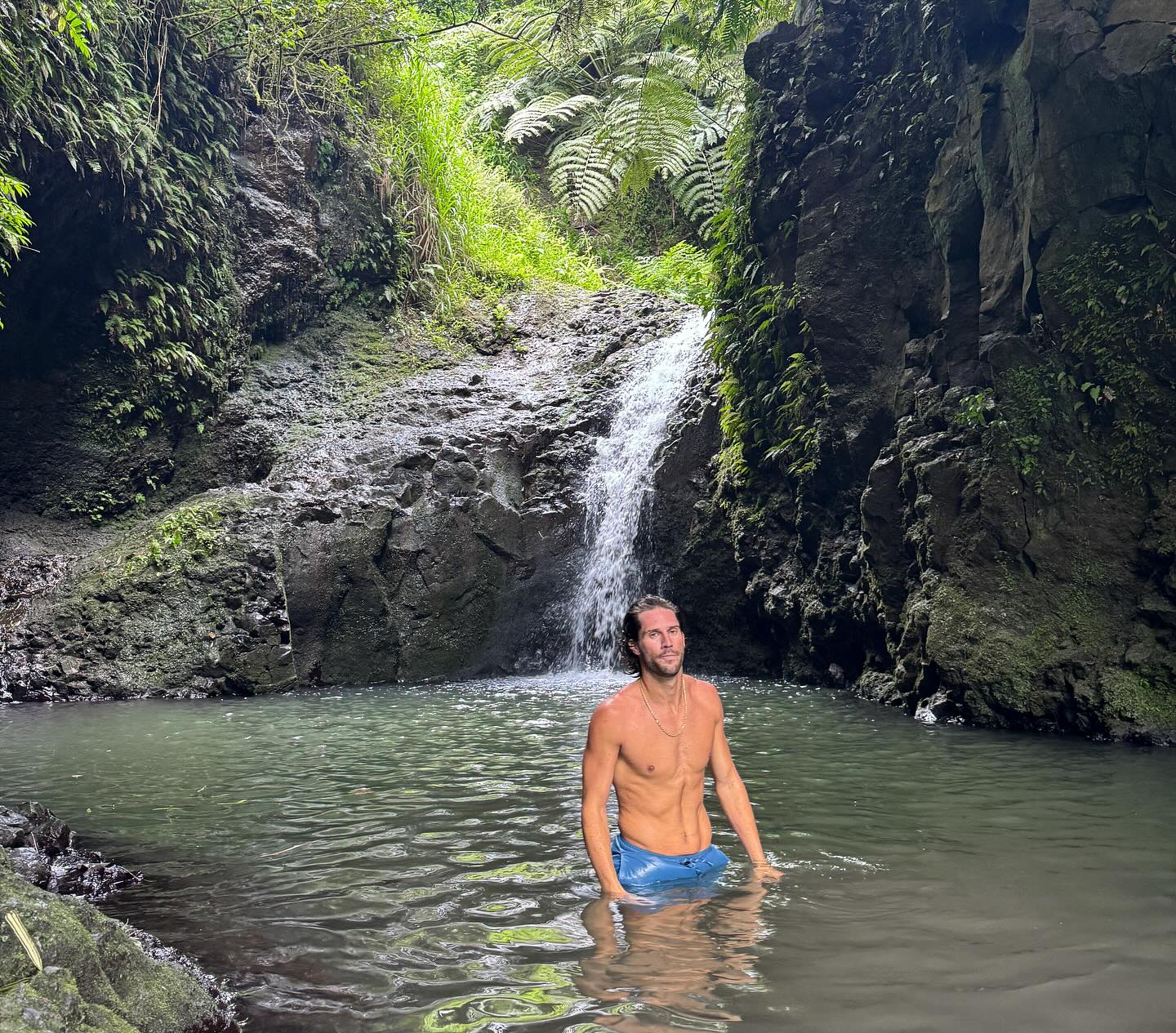 PJ Conley posing in a natural pool with a waterfall behind him.